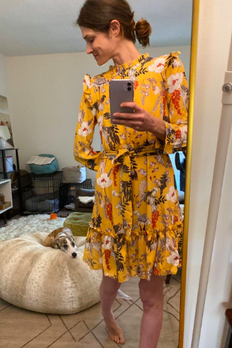 A reviewer styling the yellow floral print dress with ruffled shoulders
