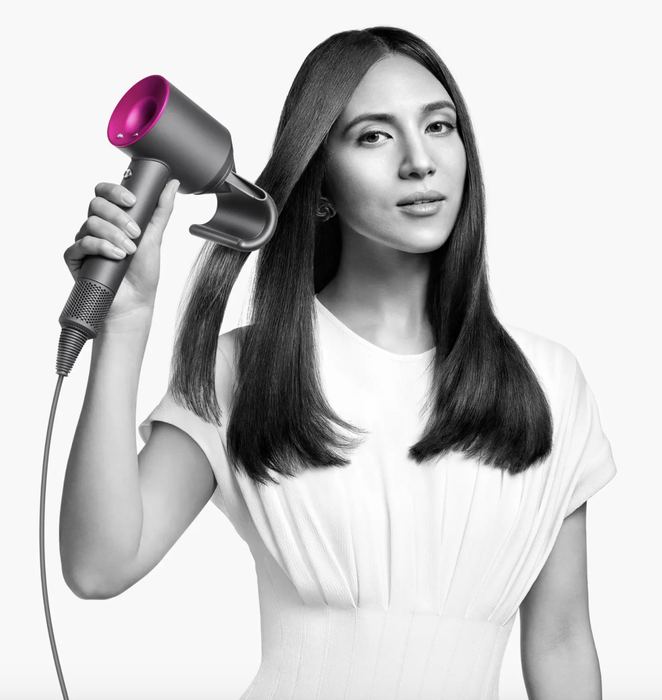 A model using the Dyson Supersonic Hair Dryer to style her hair