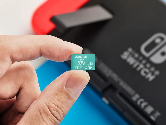 A hand gripping the 512GB SanDisk memory card.