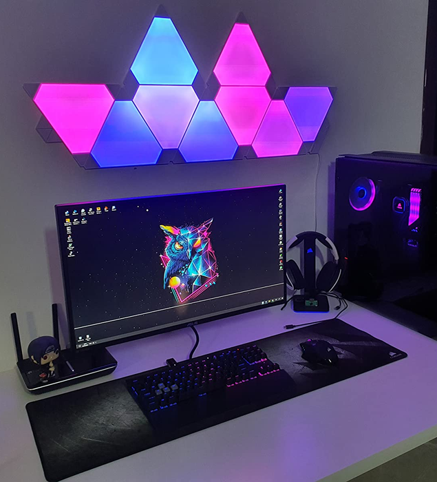 A reviewer's gaming setup illuminated with pink, blue, and purple light panels positioned neatly above their monitor.