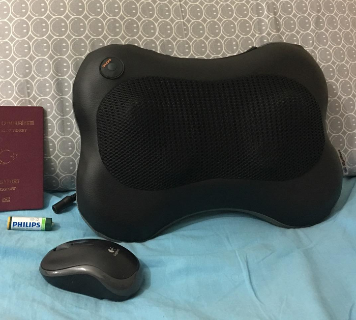 A massager pillow placed next to a mouse for size comparison.