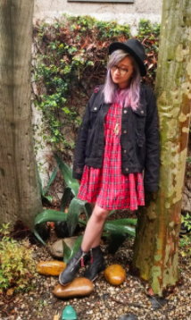 A reviewer showcasing a red dress paired with rain boots and a jacket.