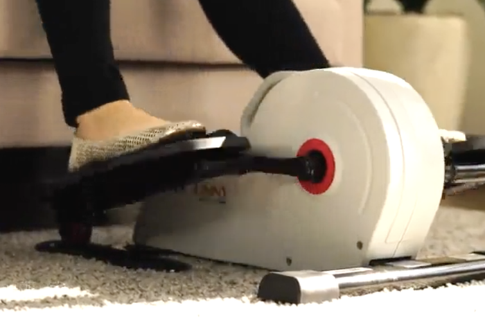 A person pedaling on the compact elliptical machine.