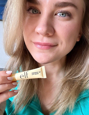 Mytourer holding the e.l.f. lip balm while sporting glossy lips