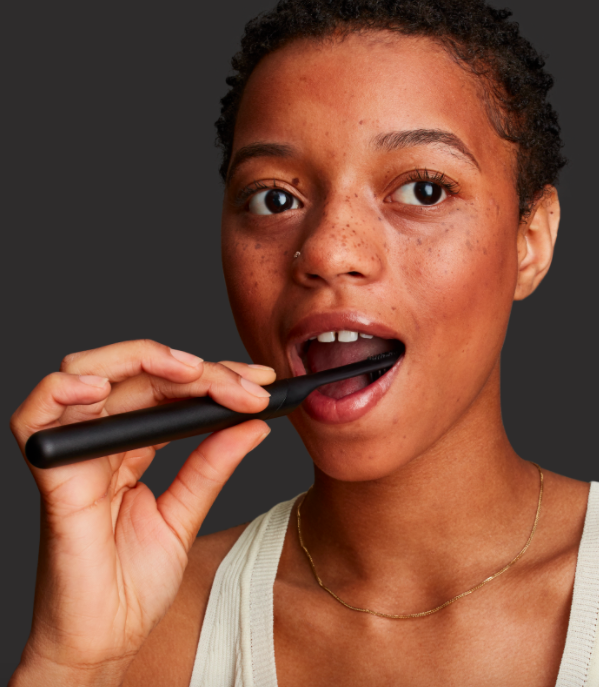 A person using the Quip toothbrush to brush their teeth