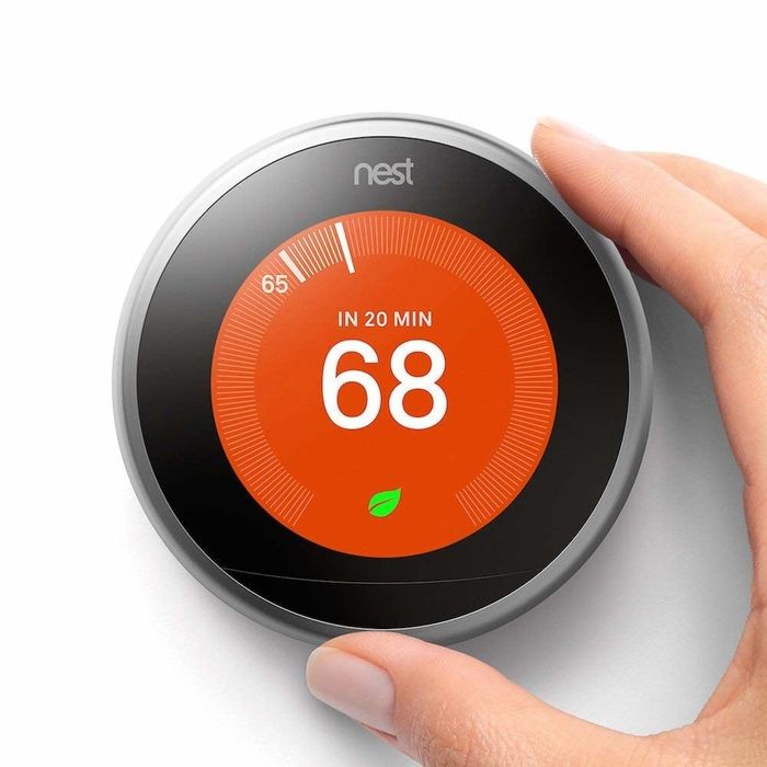 A hand adjusting the temperature on the Nest thermostat.