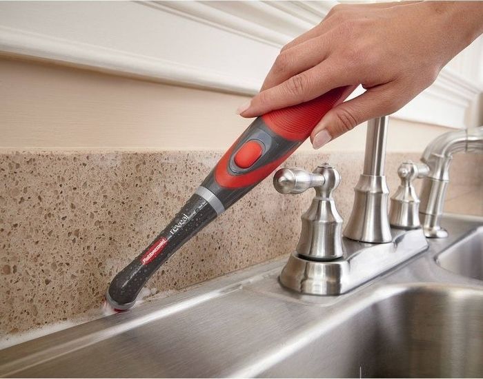 A scrubbing tool is cleaning grout.