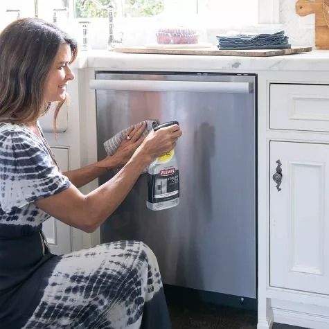 A person applying a stainless steel cleaner to a dishwasher.