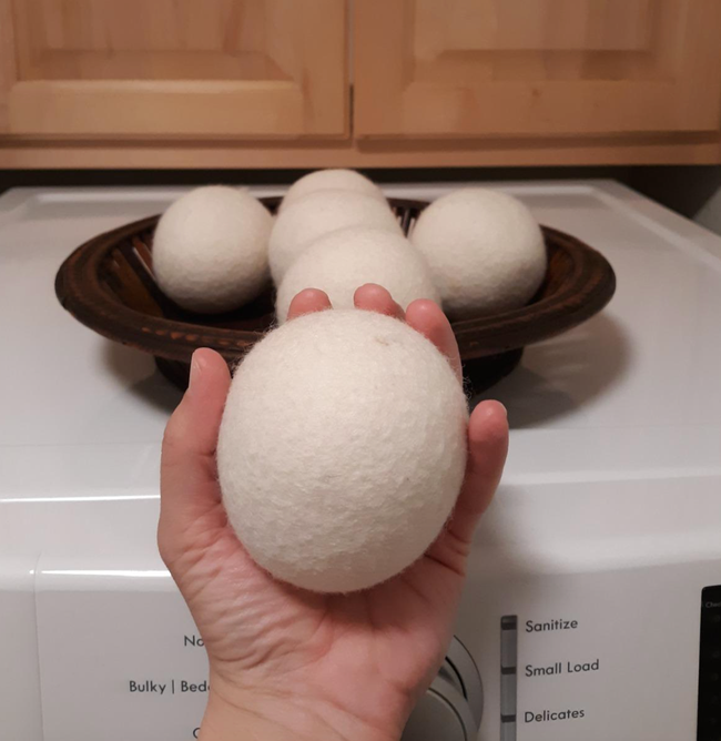Reviewer holding a white dryer ball next to a dryer