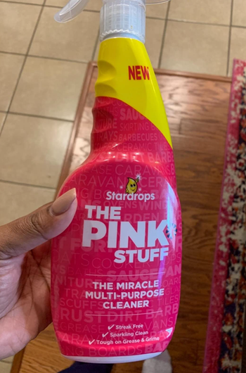 A reviewer holding a pink spray bottle