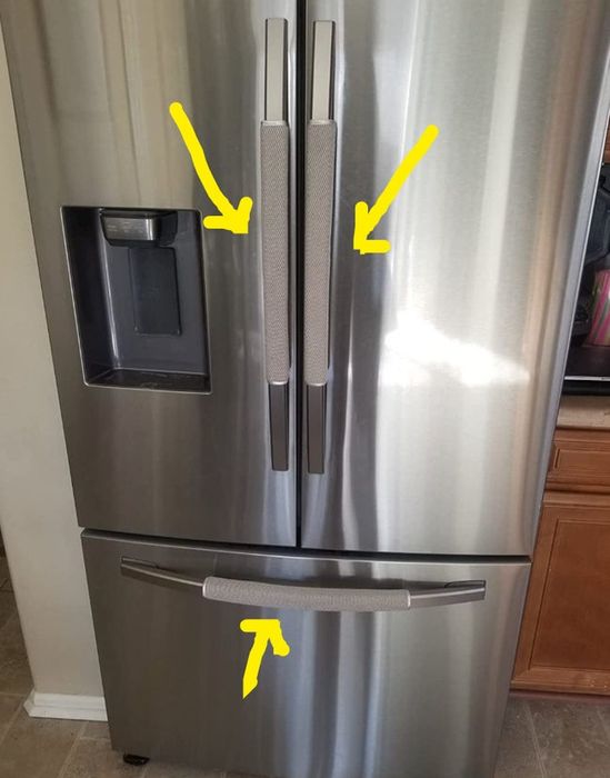 A stainless steel fridge with three doors, each handle covered by gray padded protectors