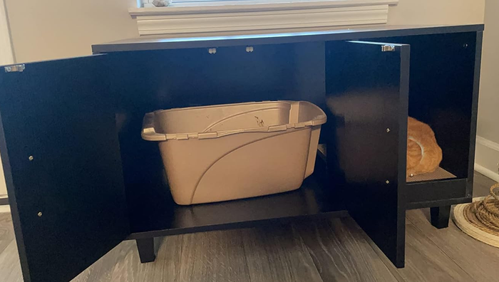 A reviewer photo showing the enclosure's cabinet doors open to reveal the litter box inside