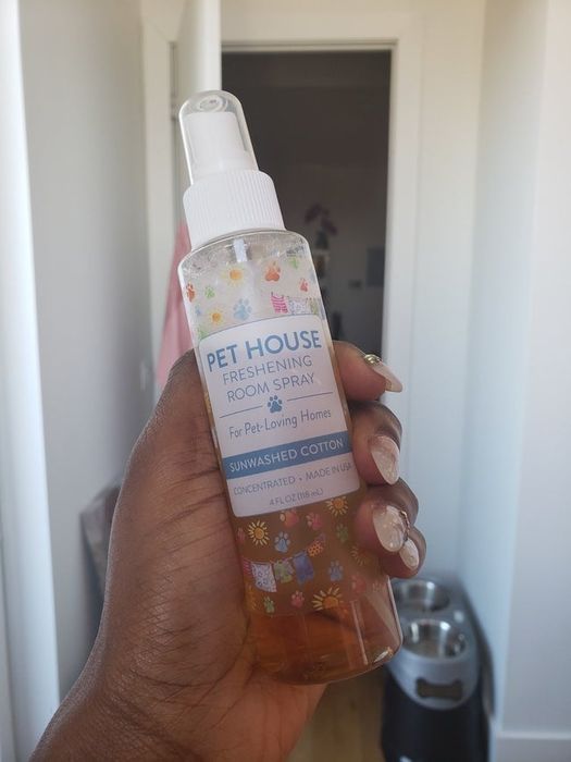 Mytour writer, Marquaysa Battle, holding the room spray with dog bowls in the background.