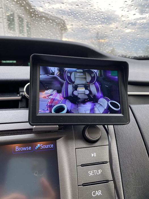 A reviewer’s photo of the monitor screen attached to their car dashboard, showing a clear view of the car seat