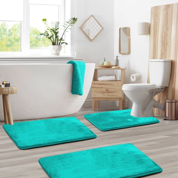 The bathroom floor features three teal bath mats, neatly laid out for a refreshing vibe.