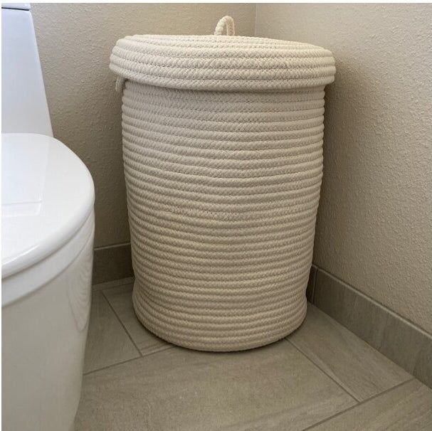 A white, rope-inspired laundry basket complete with a lid.
