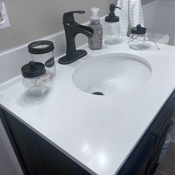 A Mason jar set resting on a bathroom sink counter.