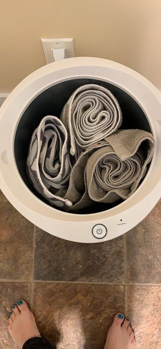A person standing in front of an open machine with towels inside