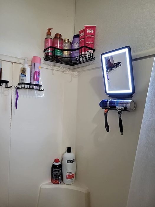 A bathroom corner filled with personal care essentials neatly arranged on shelves, complemented by a lit mirror mounted on the wall.
