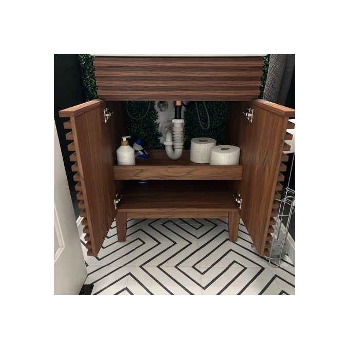 A wooden bathroom cabinet with its doors open, revealing two shelves filled with toiletries and towels.