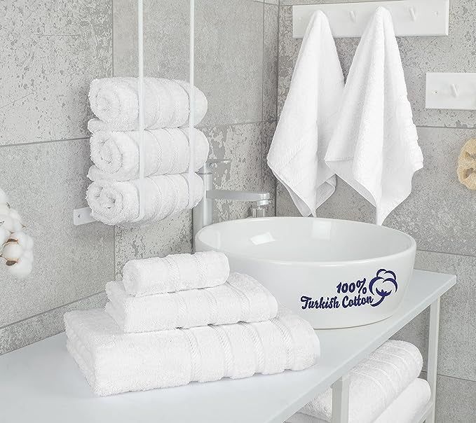 Stacked white Turkish cotton towels placed next to a sink in a bathroom