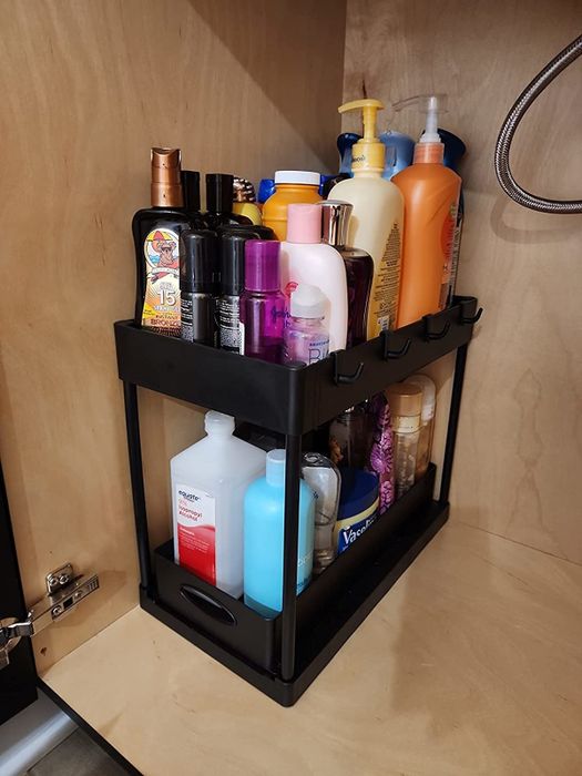 A black storage organizer filled with various personal care products, neatly arranged in a wooden cabinet for a clean, clutter-free look.
