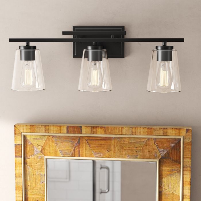 A wall-mounted light fixture featuring three elegant glass shades.