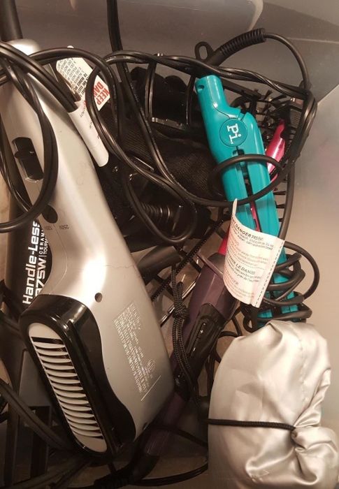 A metal basket with hair tools tangled inside