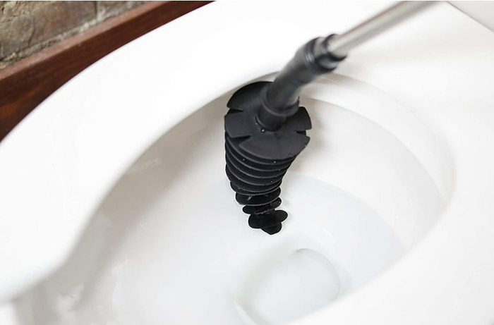 The black, cone-shaped toilet plunger resting against the edge of a toilet bowl