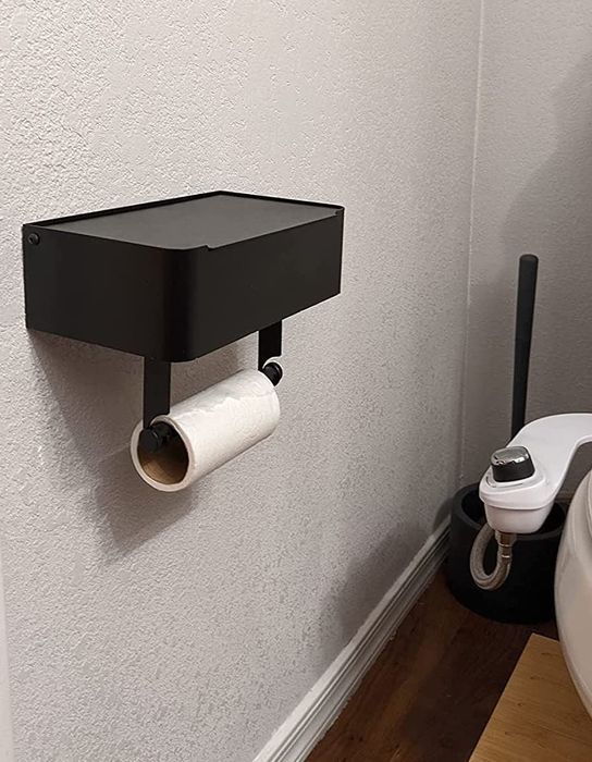 A wall-mounted toilet paper holder designed to accommodate a single roll, conveniently located near the toilet.
