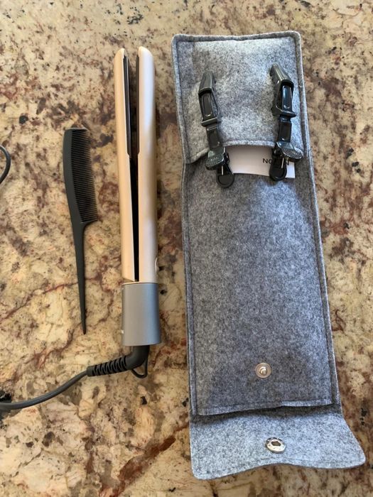 A reviewer’s image showing a gold straightener placed next to a black comb and a gray carrying case