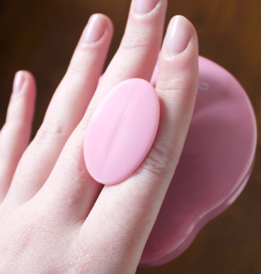 a reviewer demonstrating how comfortably the pink scalp massager brush fits between their fingers