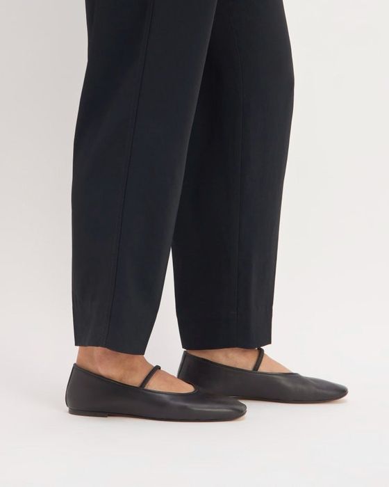 A person wearing black ballet flats featuring strap details