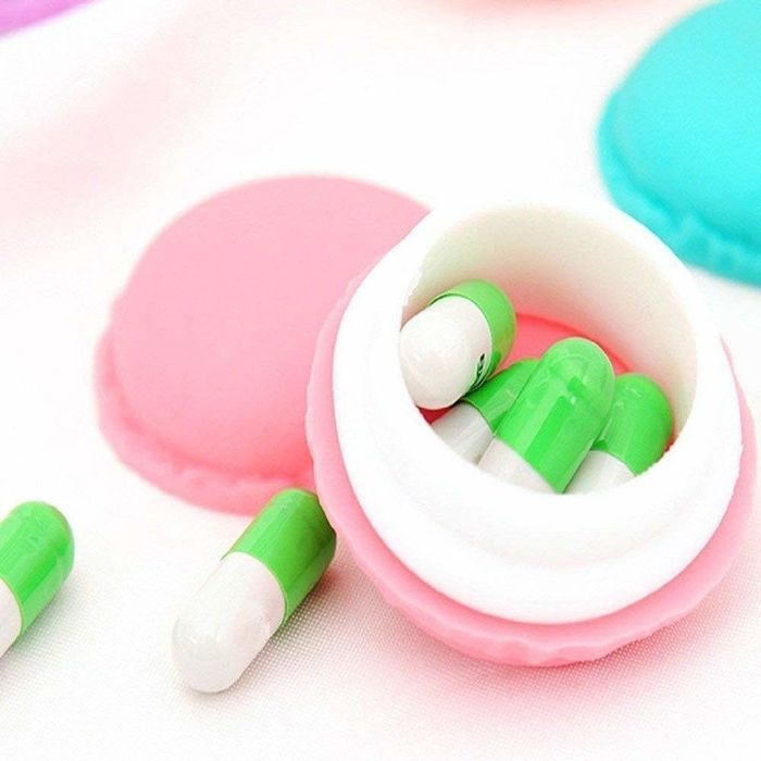 A macaron container opened to reveal pills inside