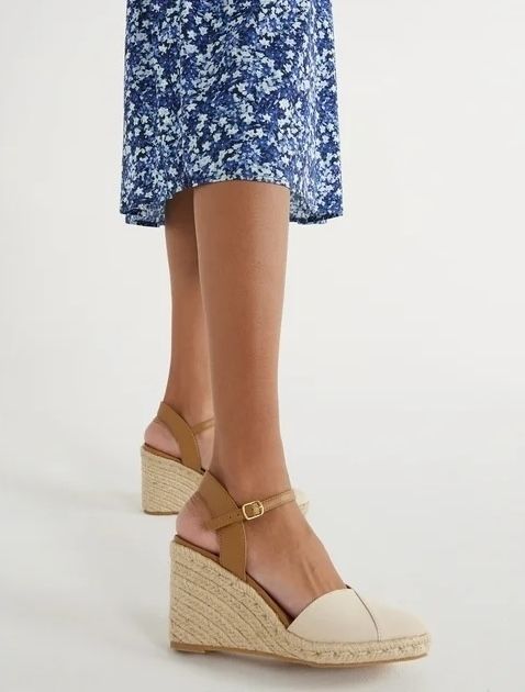 A person stands wearing wedge sandals and a floral print skirt, highlighting the footwear for a shopping context.
