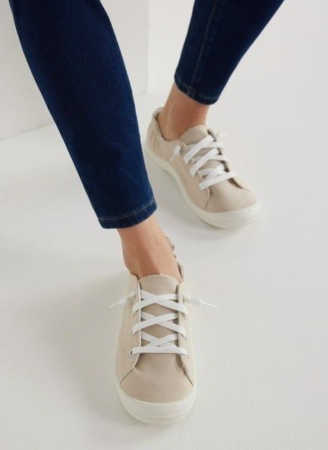 A person tying the laces of beige casual sneakers