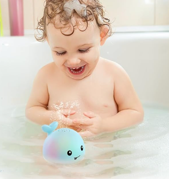 A child enjoying playtime with the whale bath toy in the tub