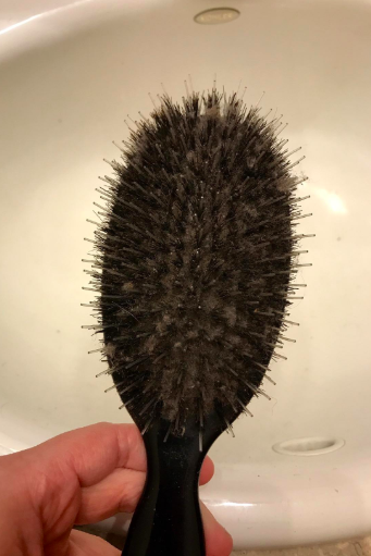 A reviewer’s hairbrush completely clogged with hair, to the point where the base holding the bristles is no longer visible.