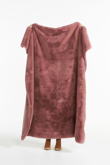 Model holding a mauve blanket, demonstrating its length, which nearly matches their height