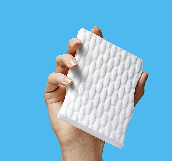 A hand holding a white square sponge.