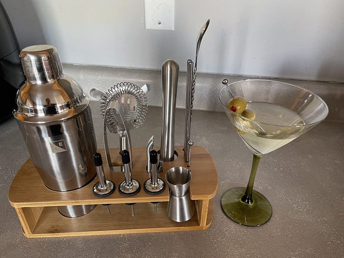 A bartending set placed next to a martini glass.
