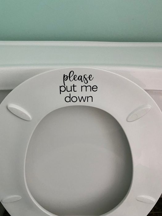 A small sticker placed on the top side of the lower part of a raised toilet seat.