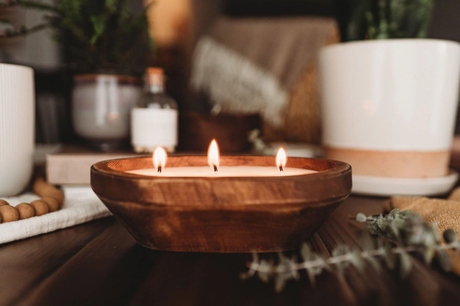 a candle glowing softly inside a wooden bowl