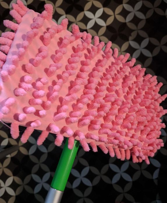 A pink microfiber slipper is attached to a Swiffer.