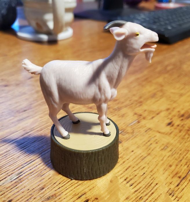 A reviewer photo featuring the screaming goat figurine placed on a desk.