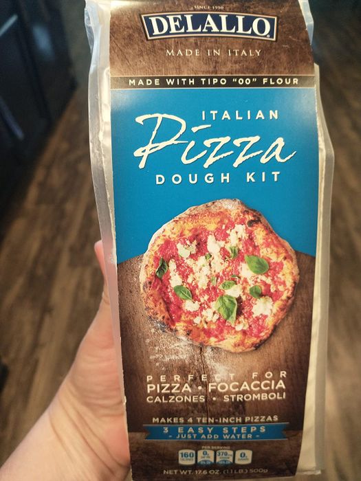someone holding a package of pizza dough