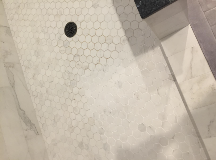 A customer-submitted photo showing the progress made on their shower floor grout after using a grout pen.