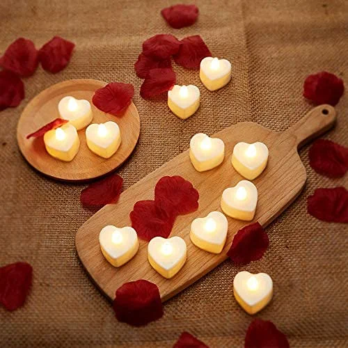 Yellow heart-shaped candles and rose petals scattered across a wooden board and plate.
