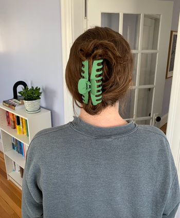 A reviewer wearing their hair up in a green claw clip.