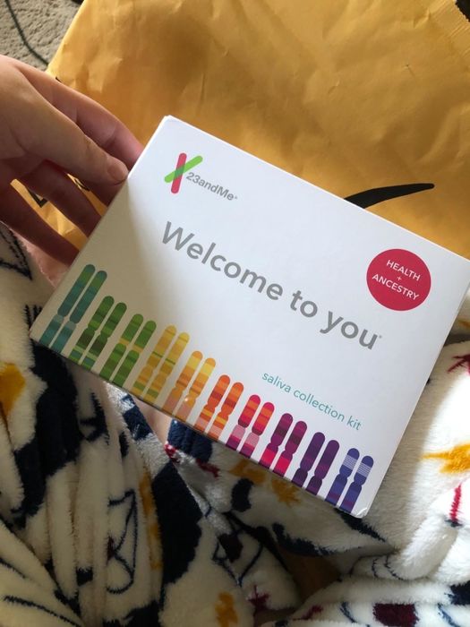 A reviewer holding the 23andMe package.